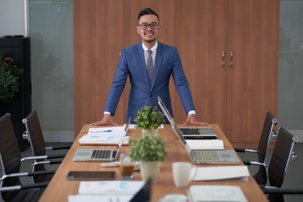 A business professional standing confidently behind a conference table